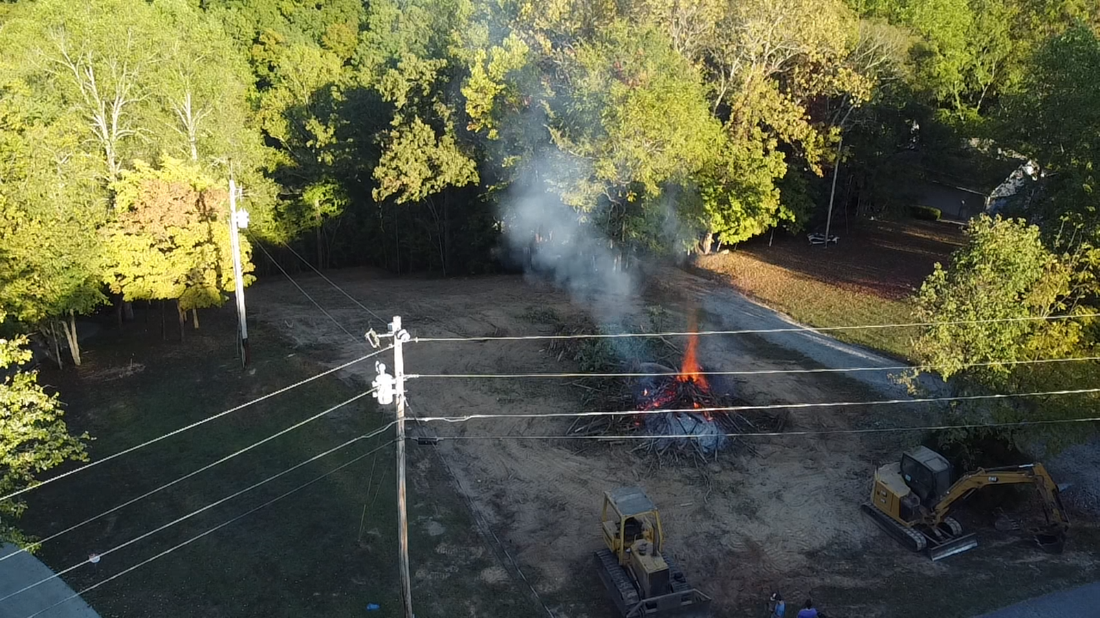 An aerial view of a fire in a yard with a lot of smoke coming out of it.