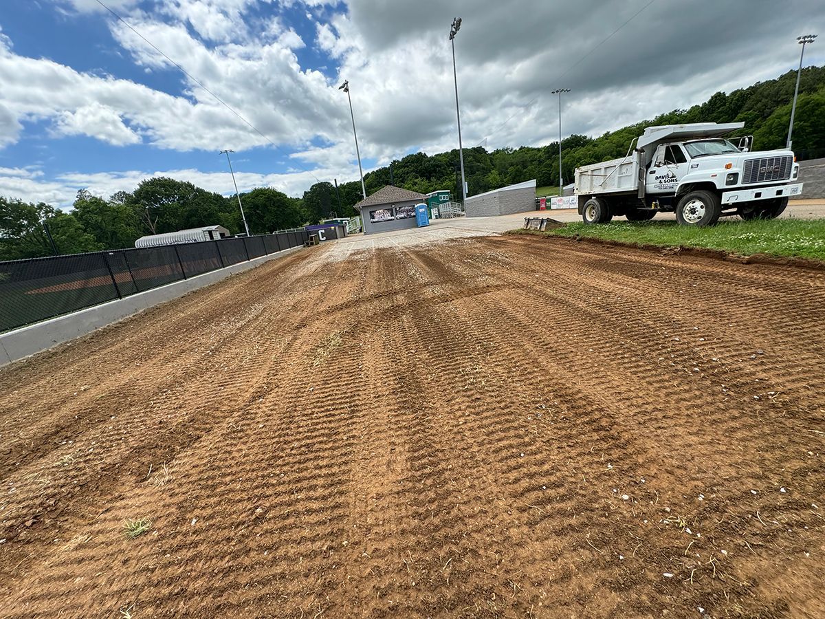 A white dump truck is parked on the side of a dirt road.