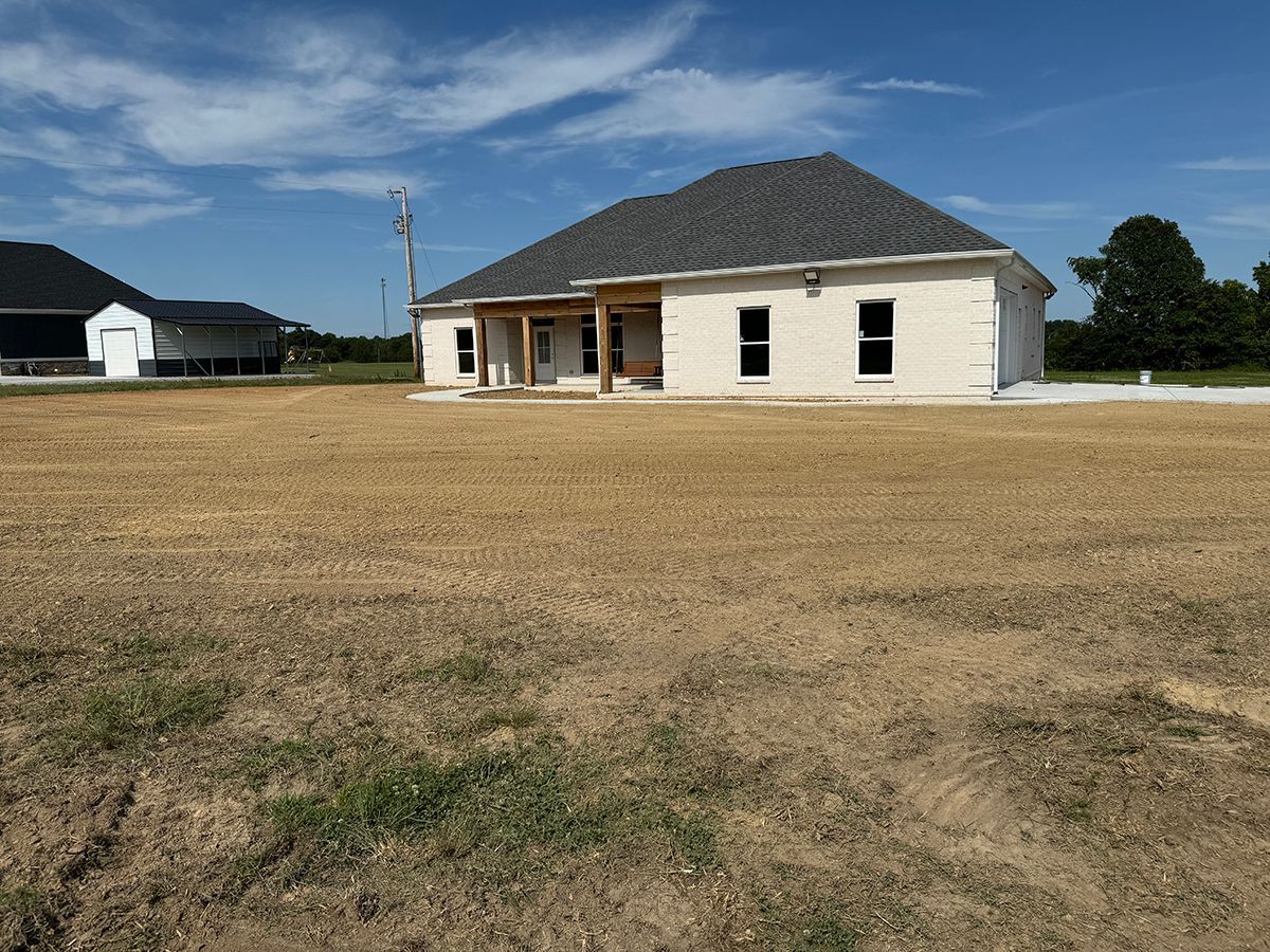 A white house is sitting in the middle of a field.