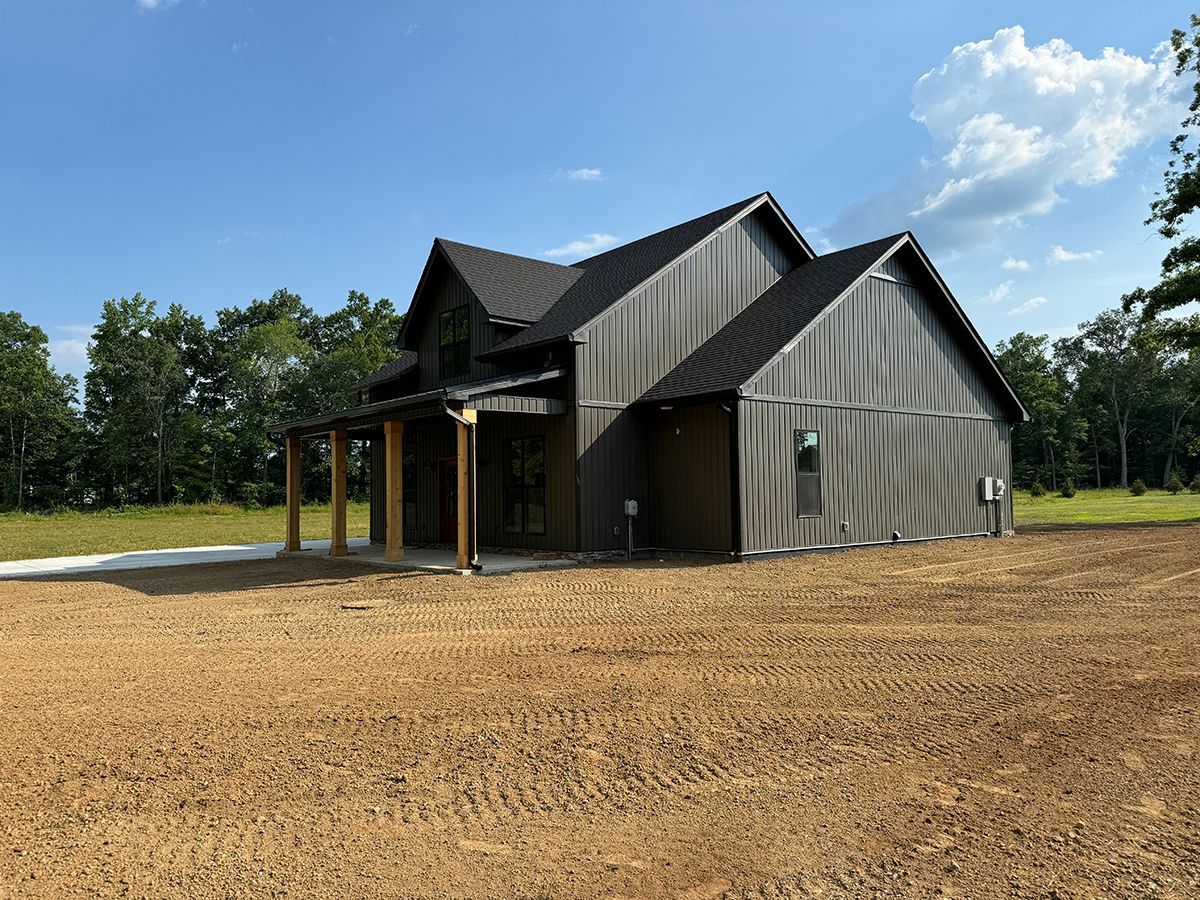 A house is sitting in the middle of a dirt field.