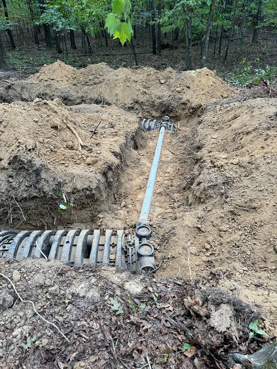 A pipe is being installed in the dirt in the woods.