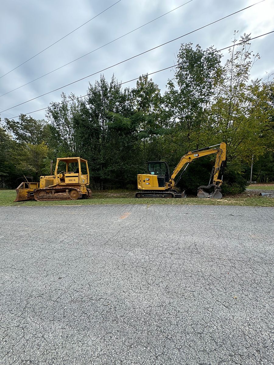 A bulldozer and an excavator are parked in a gravel lot.