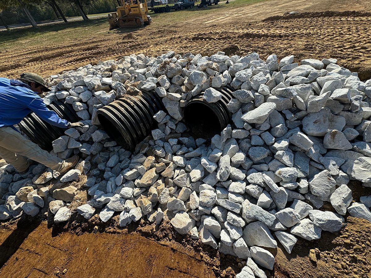 A man is laying pipes in a pile of rocks.