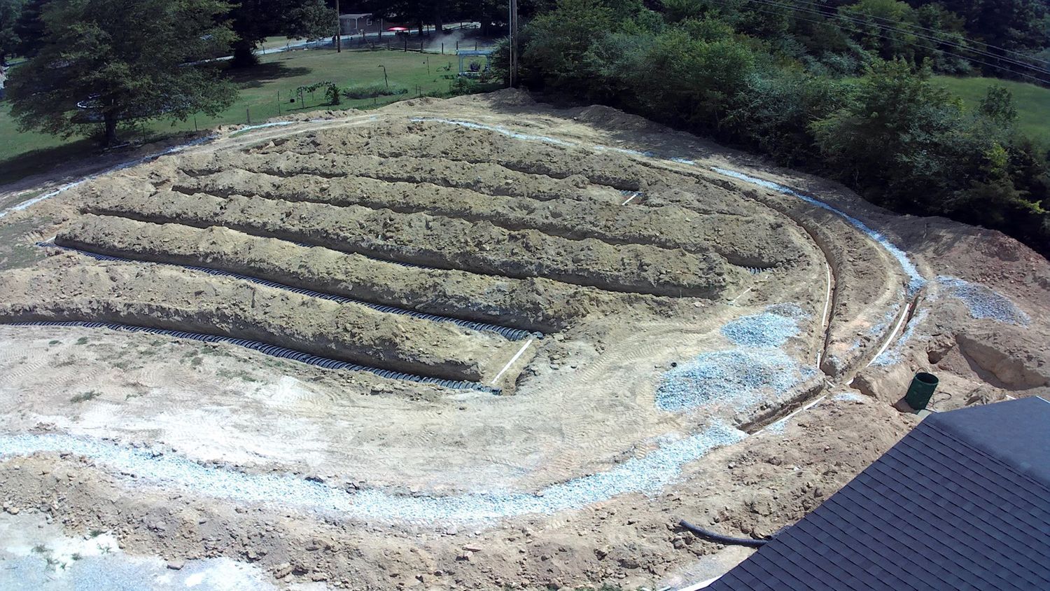 An aerial view of a dirt field with trees in the background.
