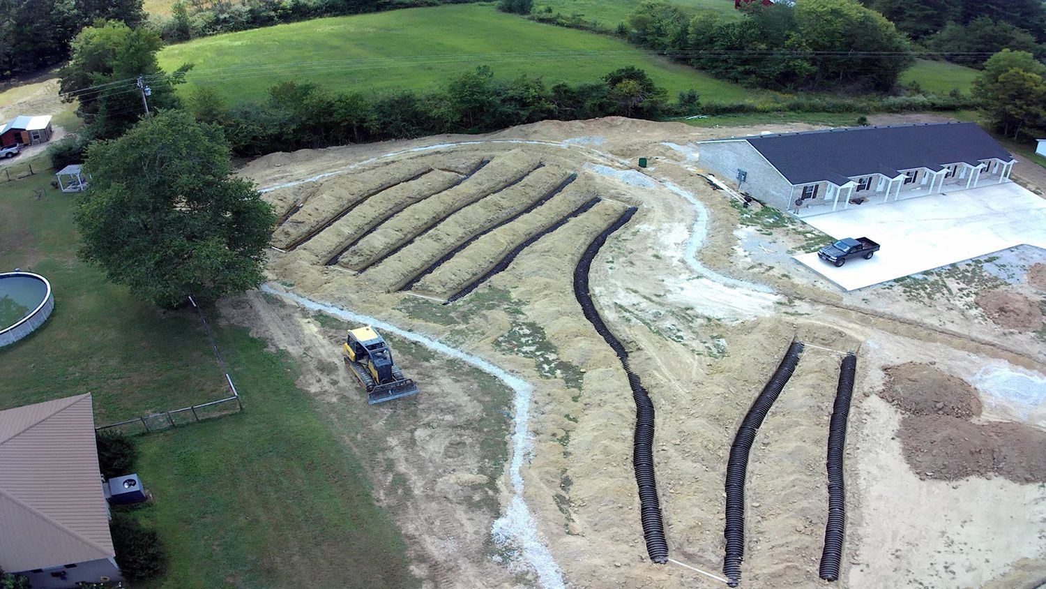 An aerial view of a dirt field with a house in the background.