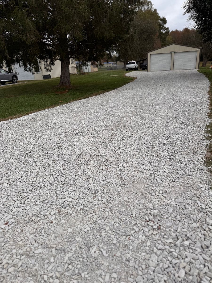 A gravel driveway leading to a garage and a house.