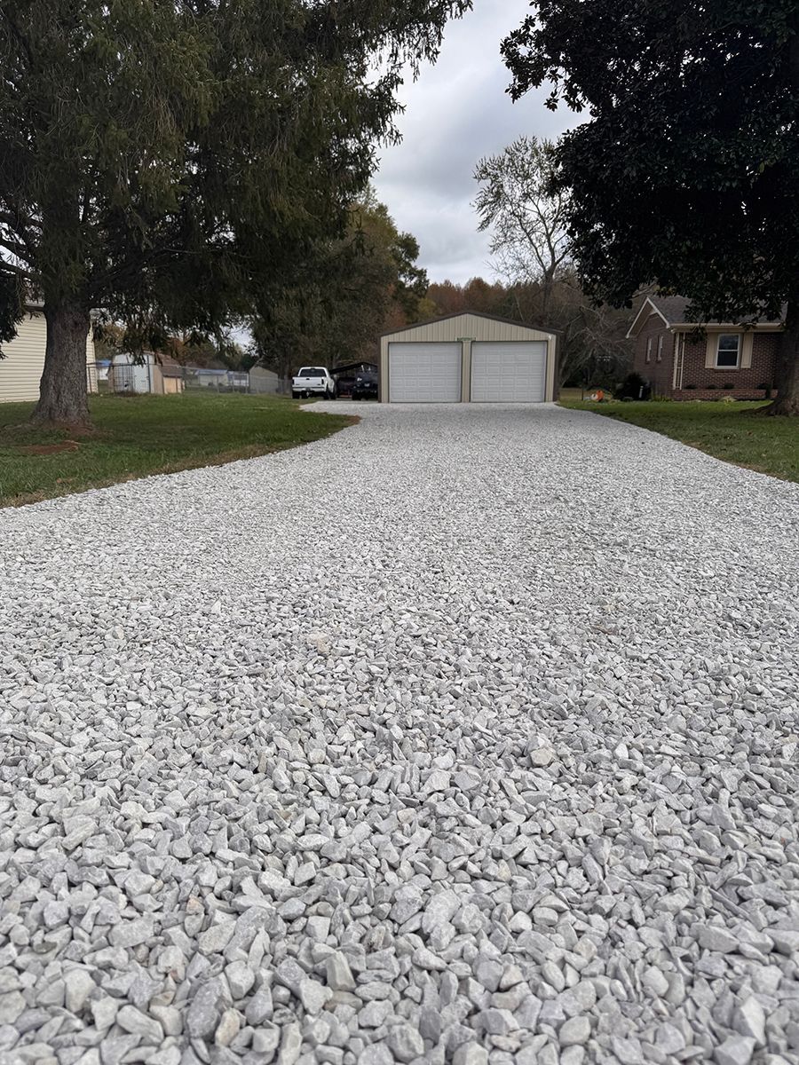 A gravel driveway with a garage in the background.