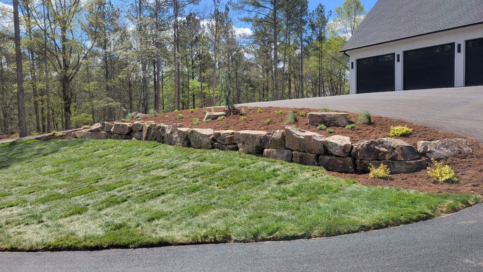 A driveway leading to a house with a garage and a lush green lawn.