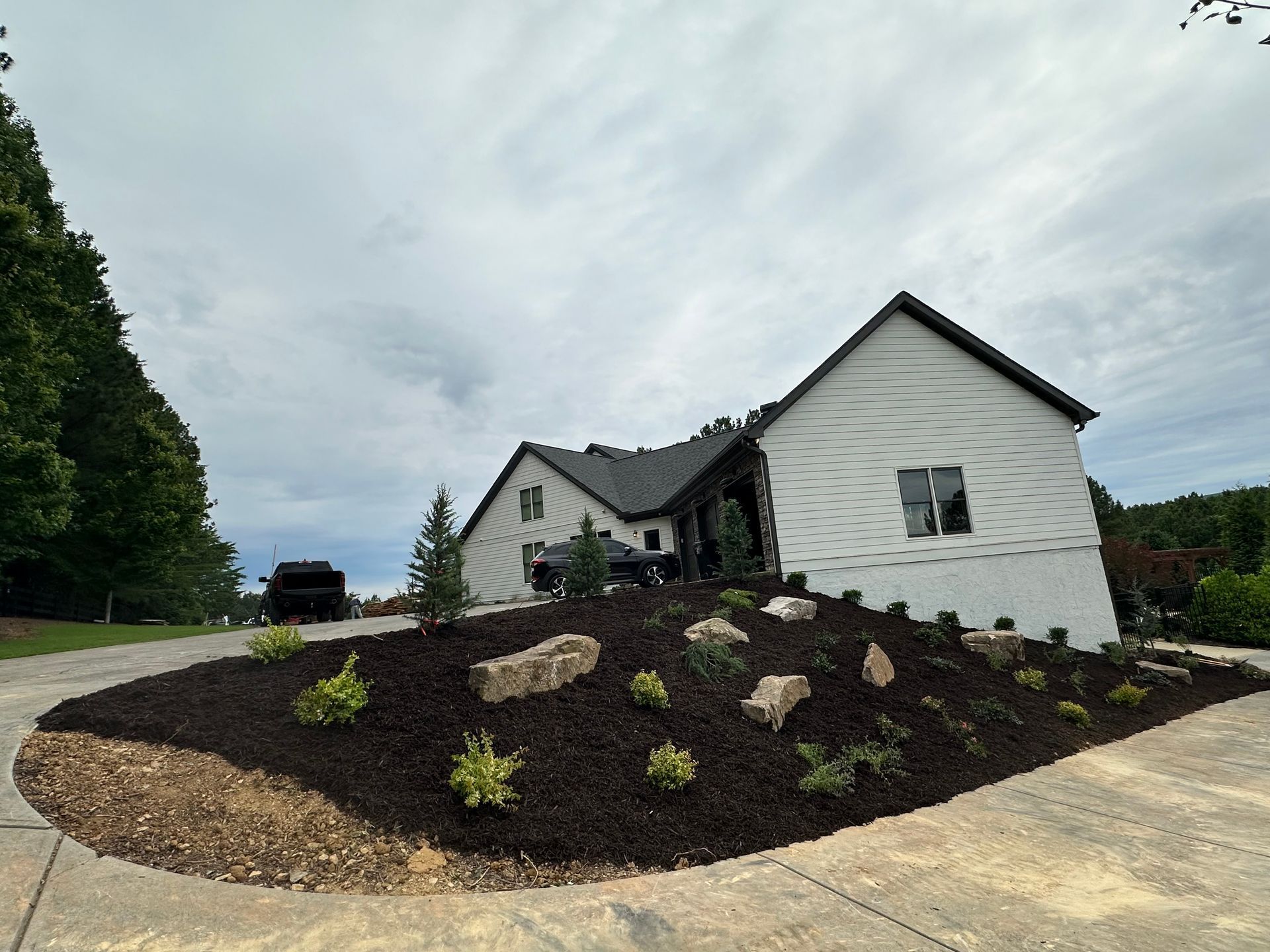 A large white house is sitting on top of a hill surrounded by trees.