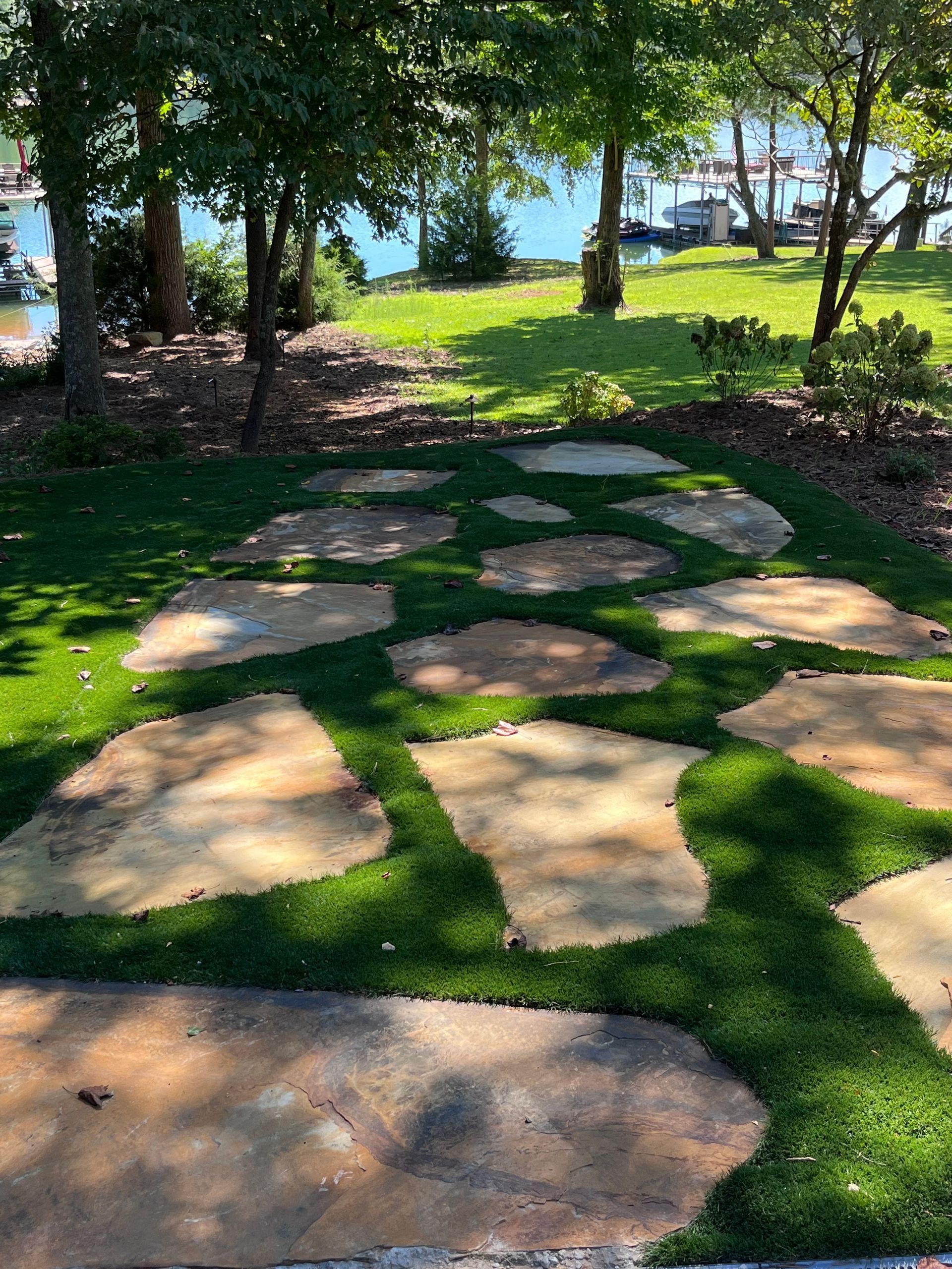 A stone walkway surrounded by grass and trees in a park.