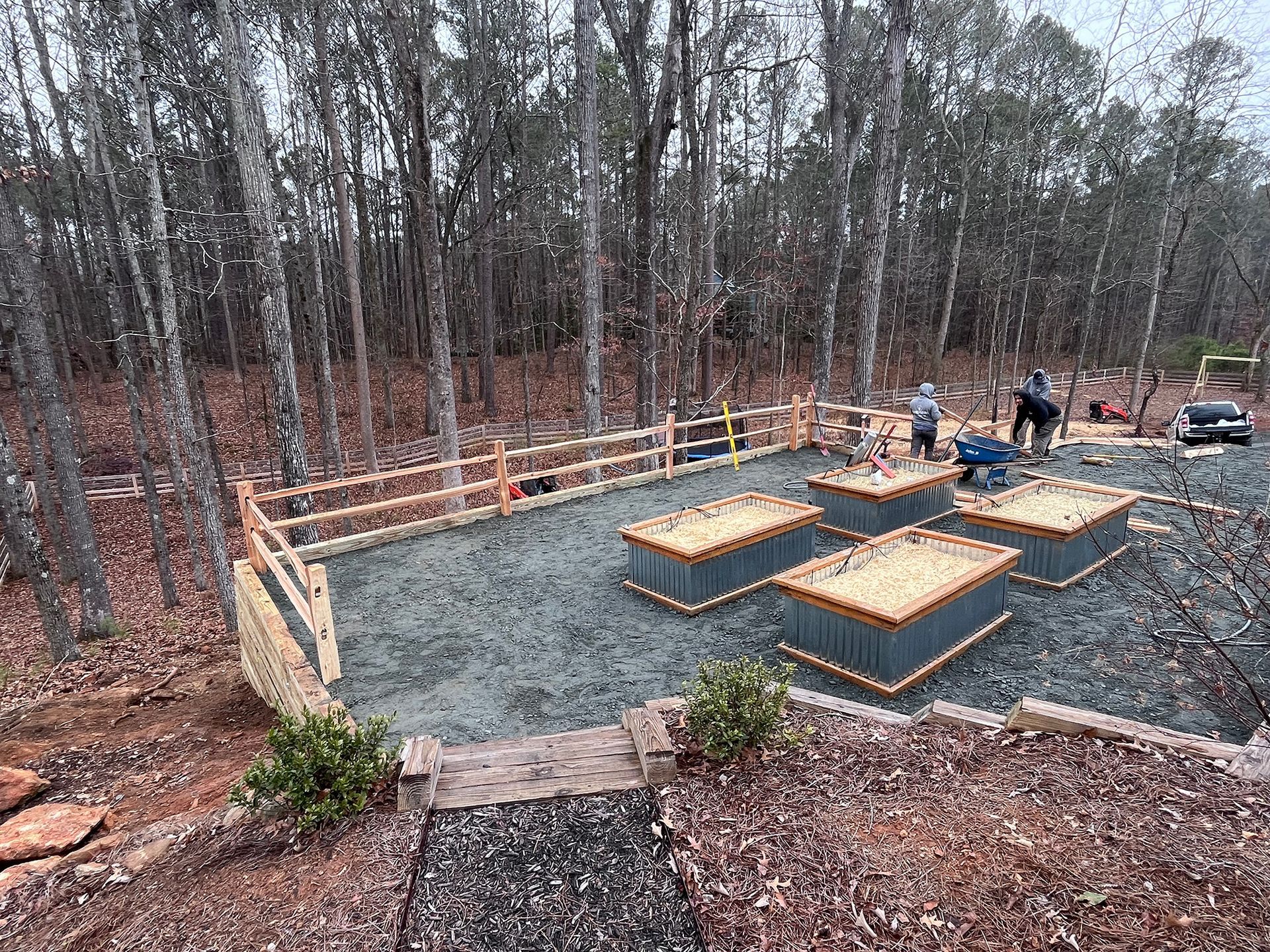 A group of people are working on a playground in the woods.