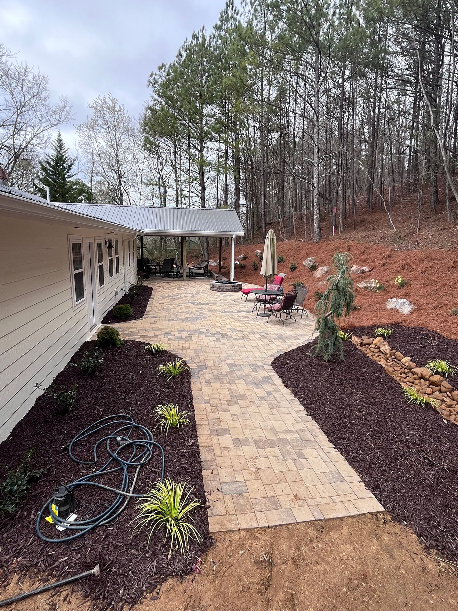 A house with a patio and a walkway leading to it surrounded by trees.