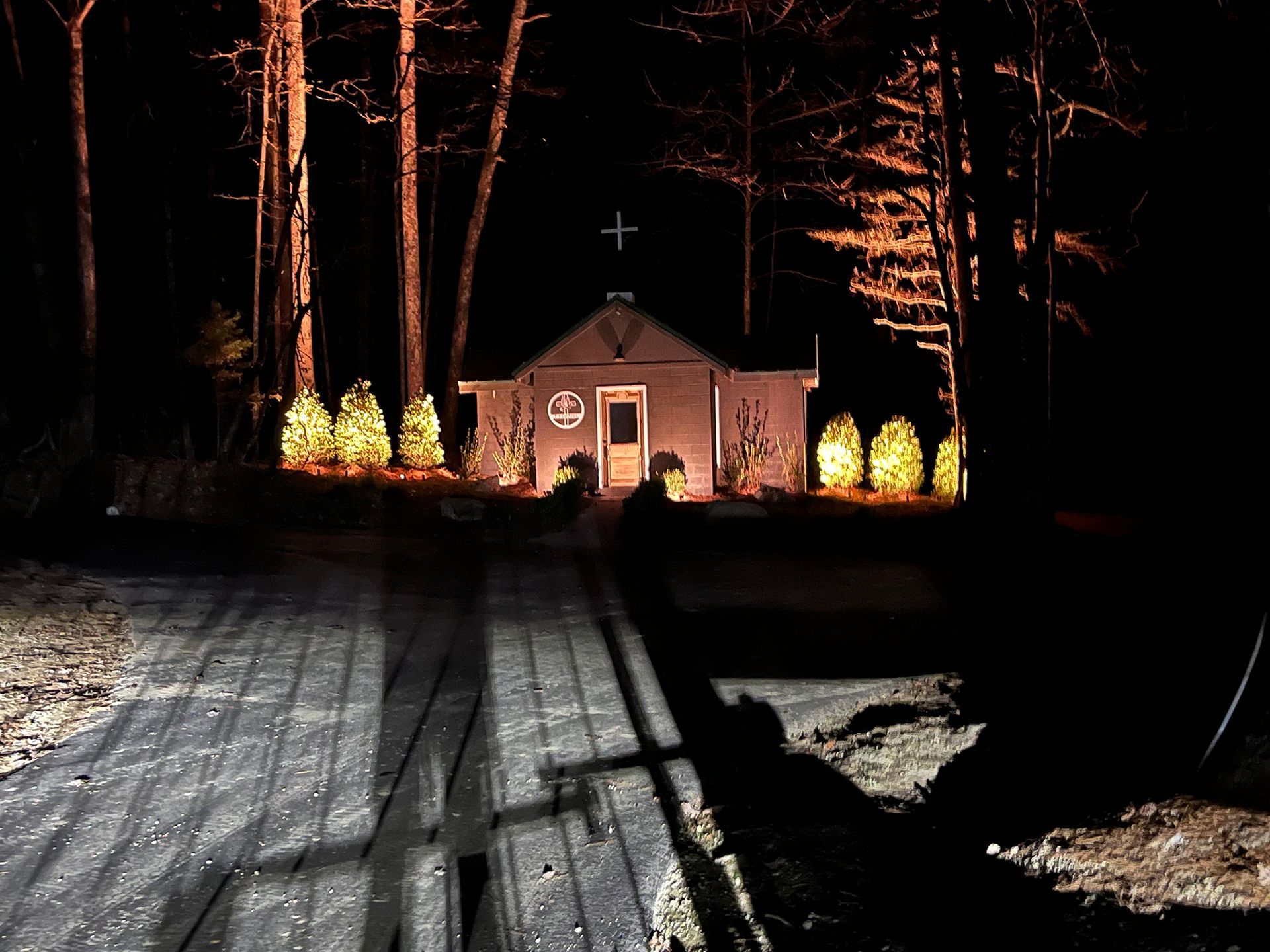 A church is lit up at night in the woods
