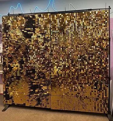 Gold sequin backdrop wall on a stand with a dark abstract pattern, indoors