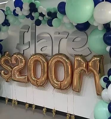 Silver “flam” letters and gold “200m” balloons on a mint, navy, and white balloon backdrop