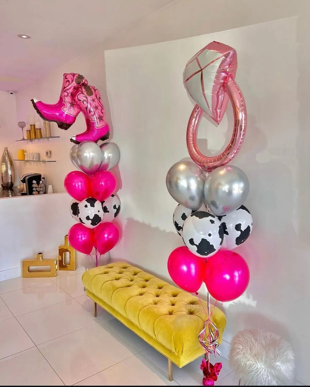 Pink cowboy boots and a flamingo balloon display beside silver, cow-print, and hot pink balloons in a white room.