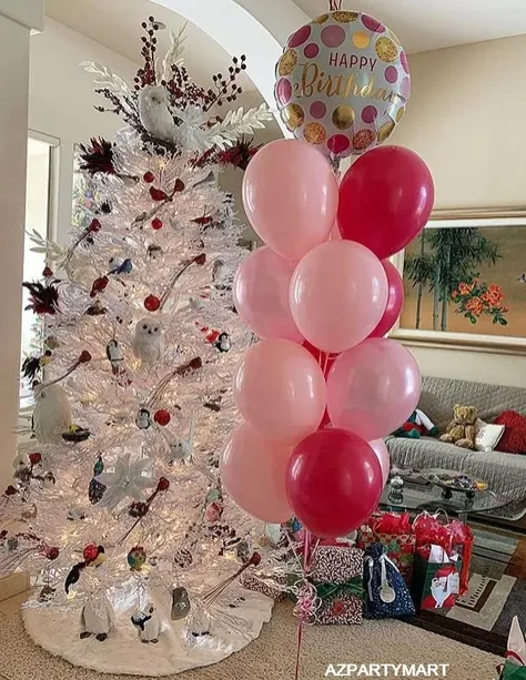 Decorated white Christmas tree beside pink and red balloons in a living room
