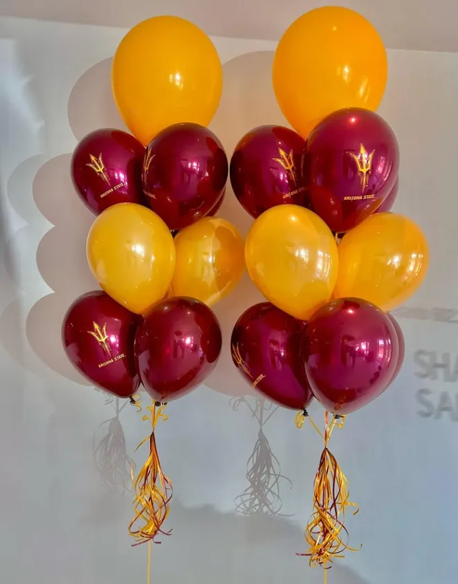 Two balloon bouquets with yellow and burgundy balloons and curling ribbons indoors