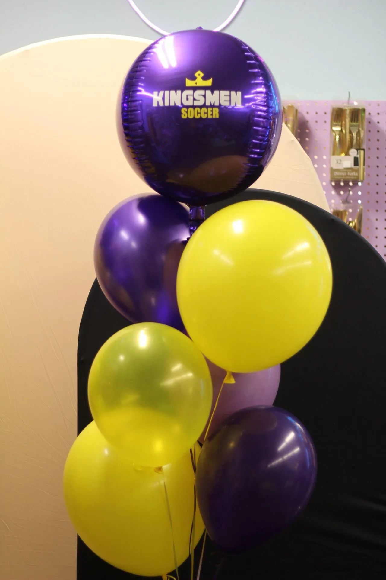 Purple and yellow balloons with a black Kingsmen SoCal balloon in a decorated indoor display