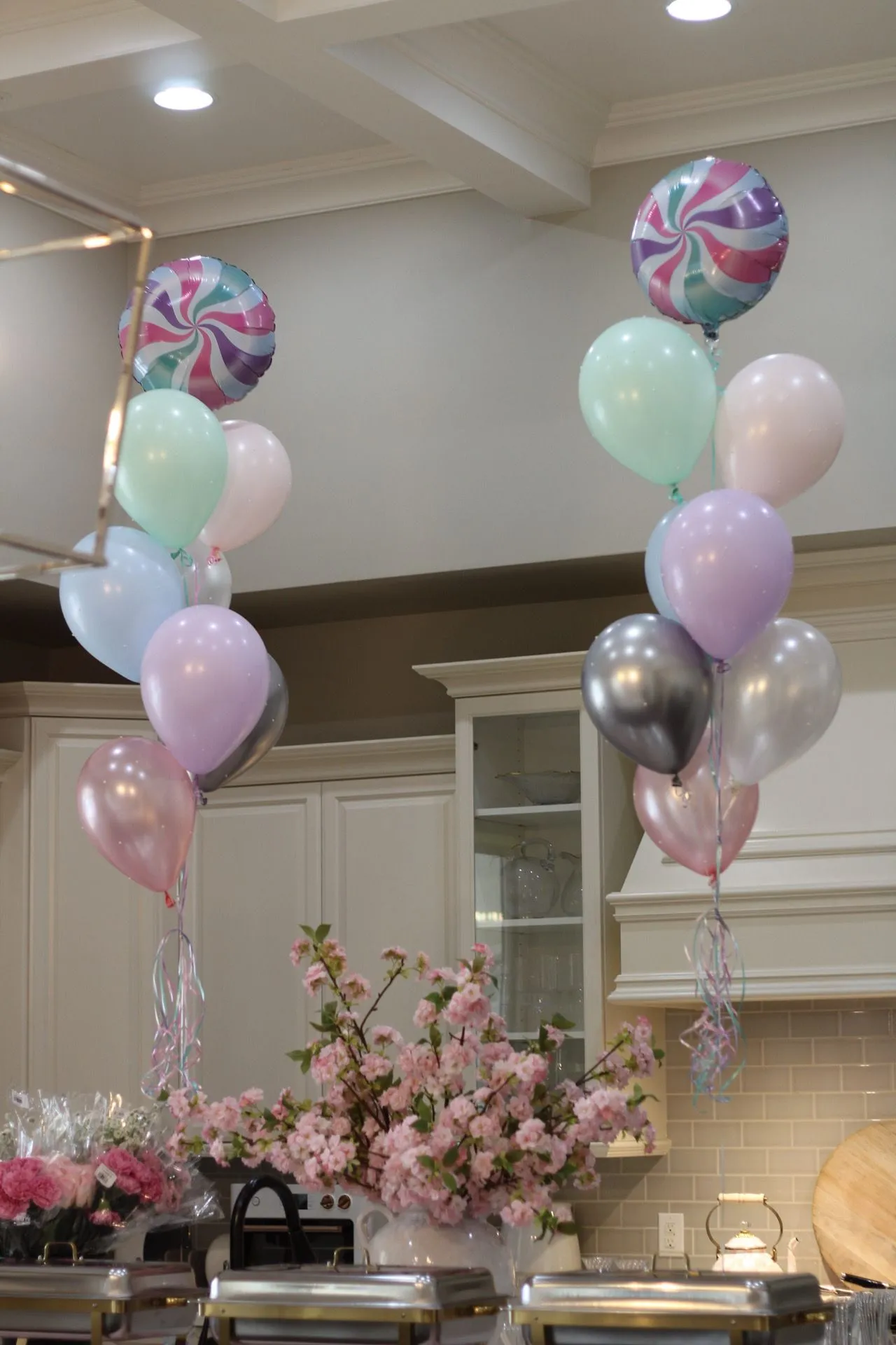Pastel balloons and floral centerpieces decorating a banquet hall dessert table