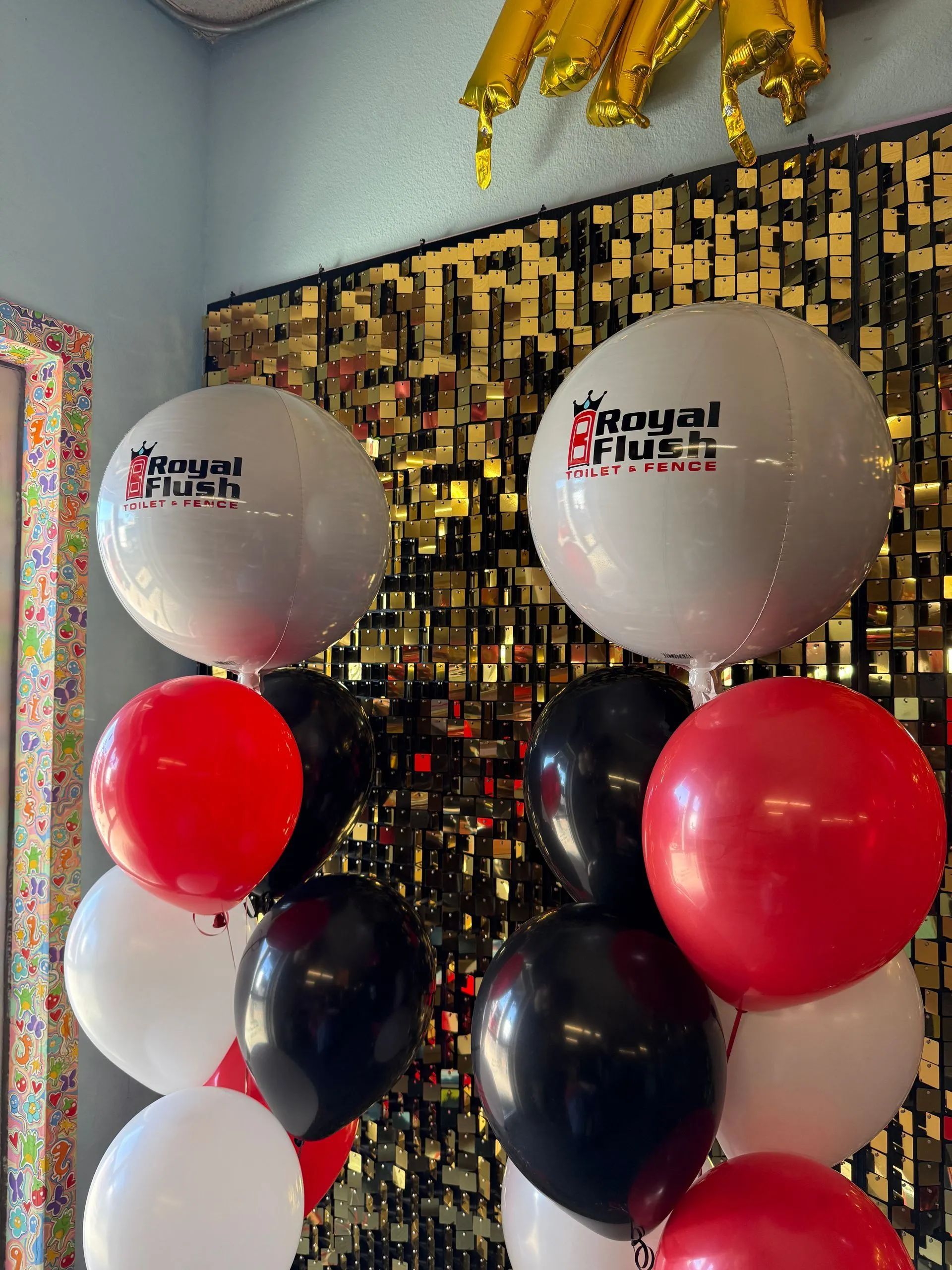 Balloon display with red, black, white, and silver balloons in front of a gold sequin backdrop.