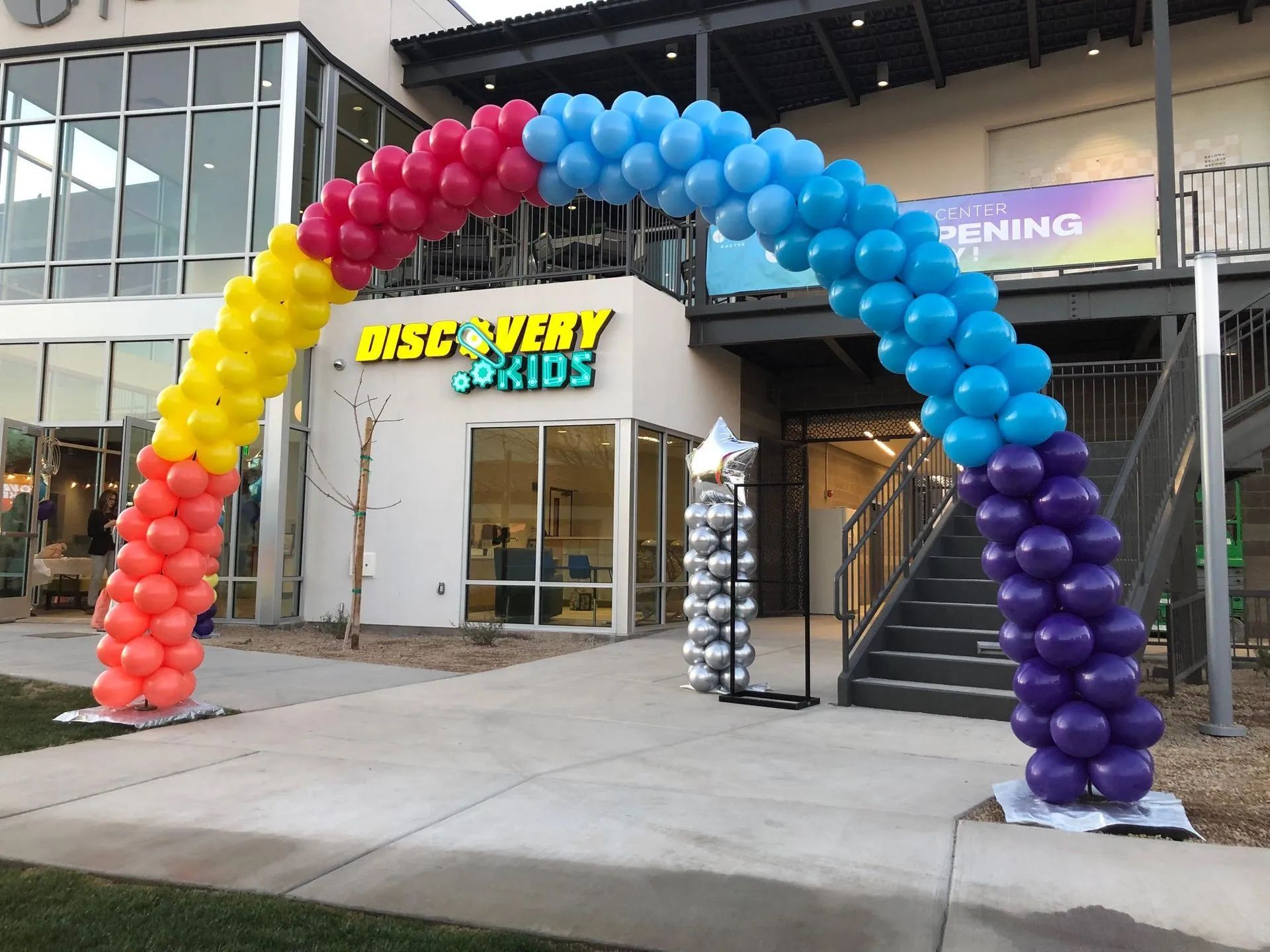 Rainbow balloon arch over the entrance to Bicycly Kids storefront at a mall entrance
