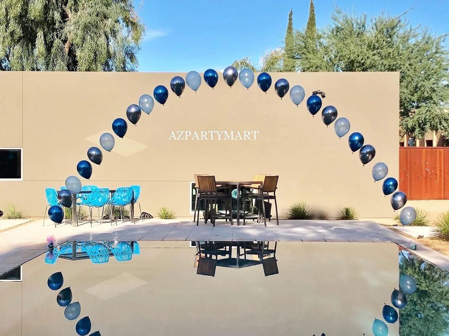 Blue-and-black balloon arch over a patio by a pool, with “APARTMENT” on the wall.