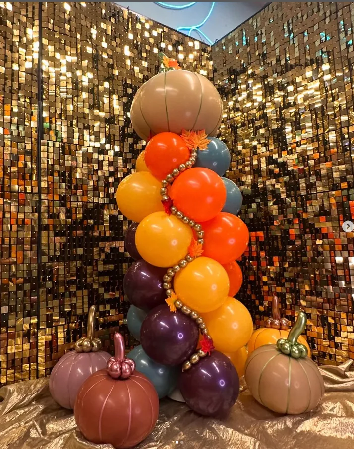 Balloon pumpkin tower in orange, purple, and beige on a sparkling gold backdrop