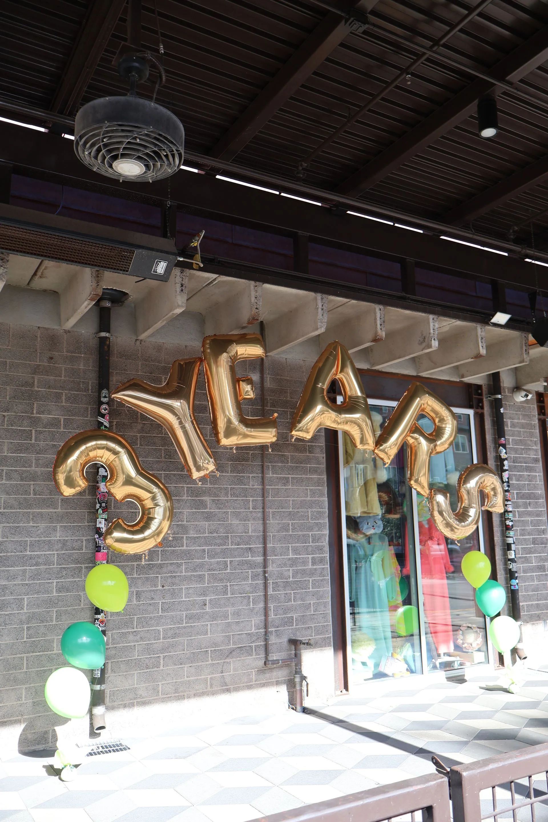 Gold “3 YEARS” balloon display with pastel balloons in a storefront entrance