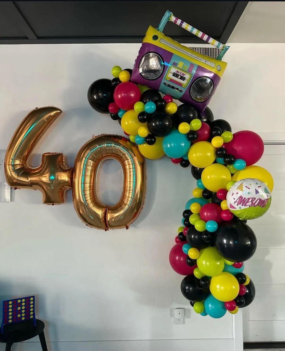 Gold “40” balloons with a colorful balloon garland and a boombox-shaped balloon decoration for a birthday party