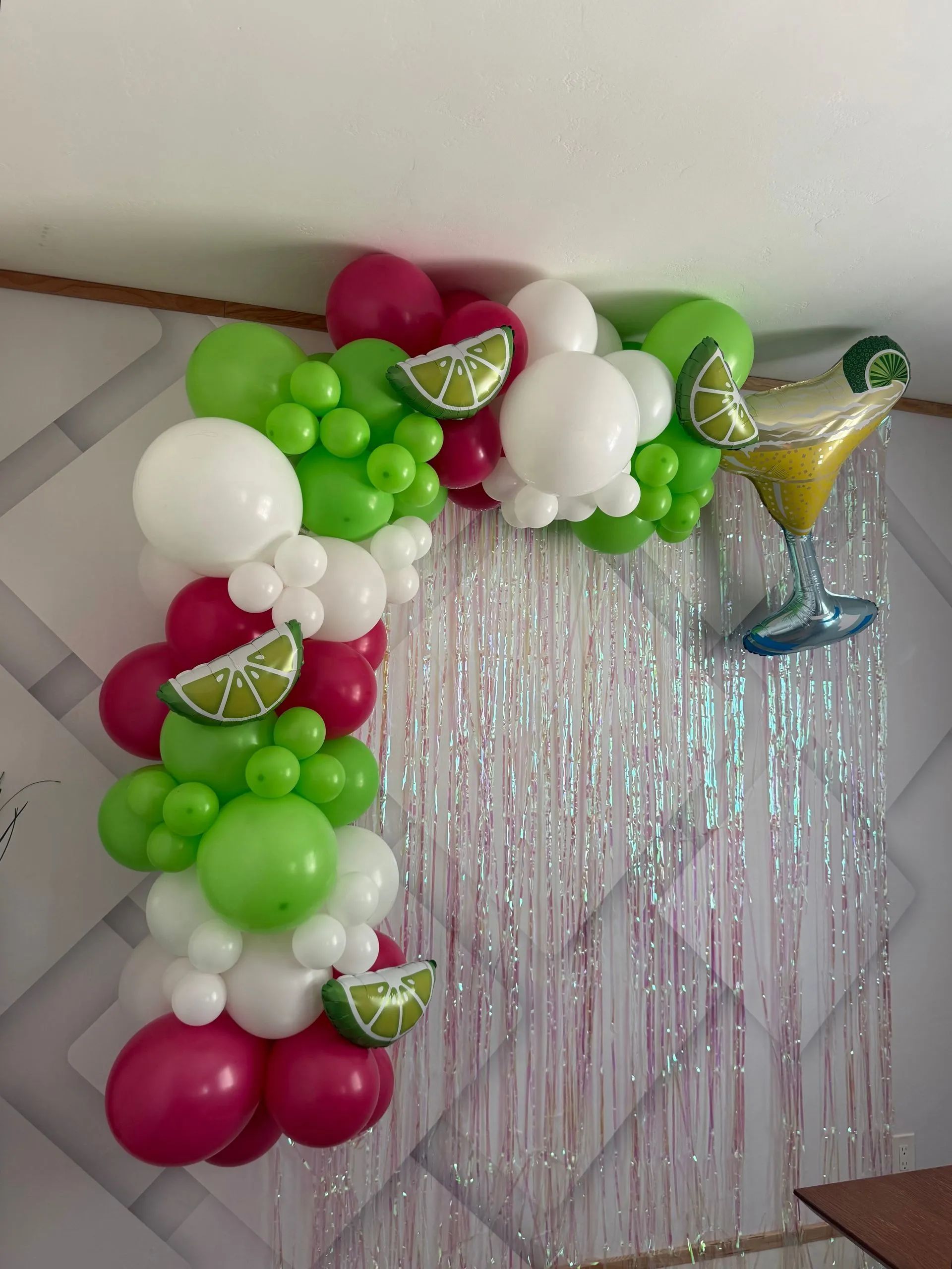 Colorful balloon arch with lime, white, pink, and silver balloons framing a shimmering backdrop and star balloons