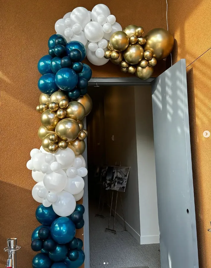 Doorway decorated with blue, white, and gold balloon garland leading into a hallway