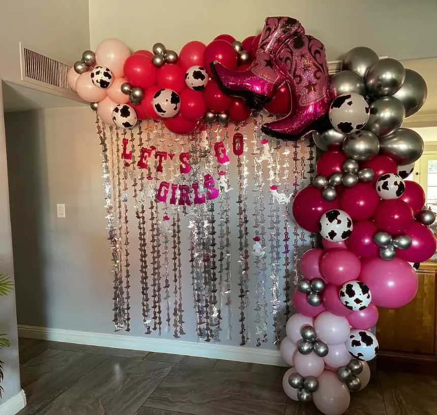 Pink and silver balloon arch with soccer balls and a “Let’s go girls” backdrop for a party