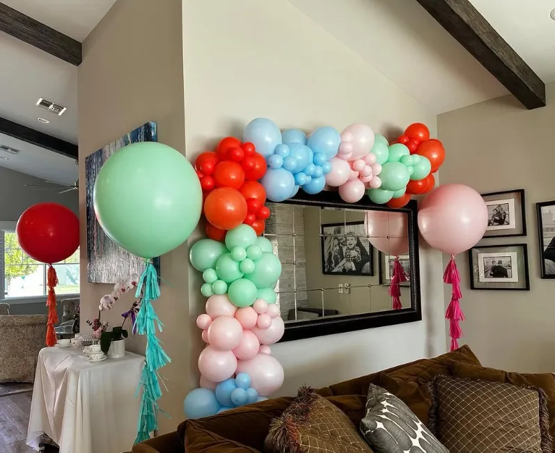 Pastel balloon garland framing a living room mirror above a couch, with large mint and pink balloons on the sides