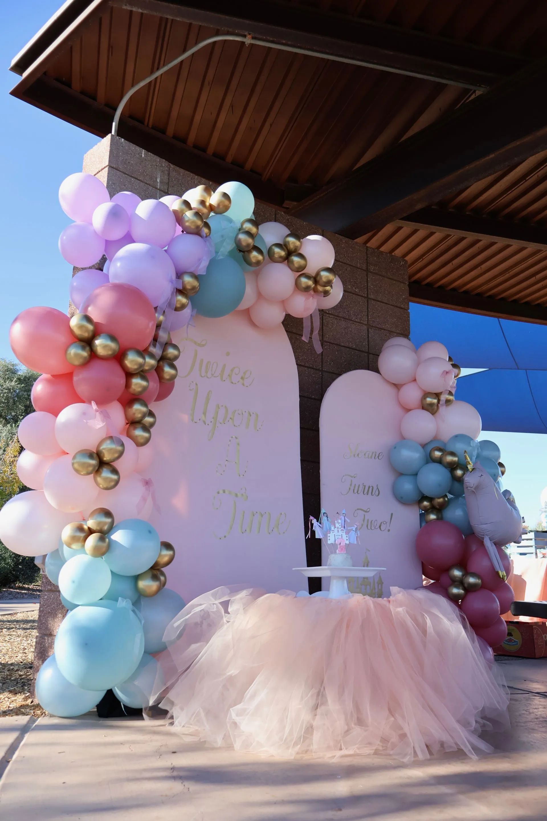 Pastel balloon backdrop with a pink tulle table setup for a baby shower celebration