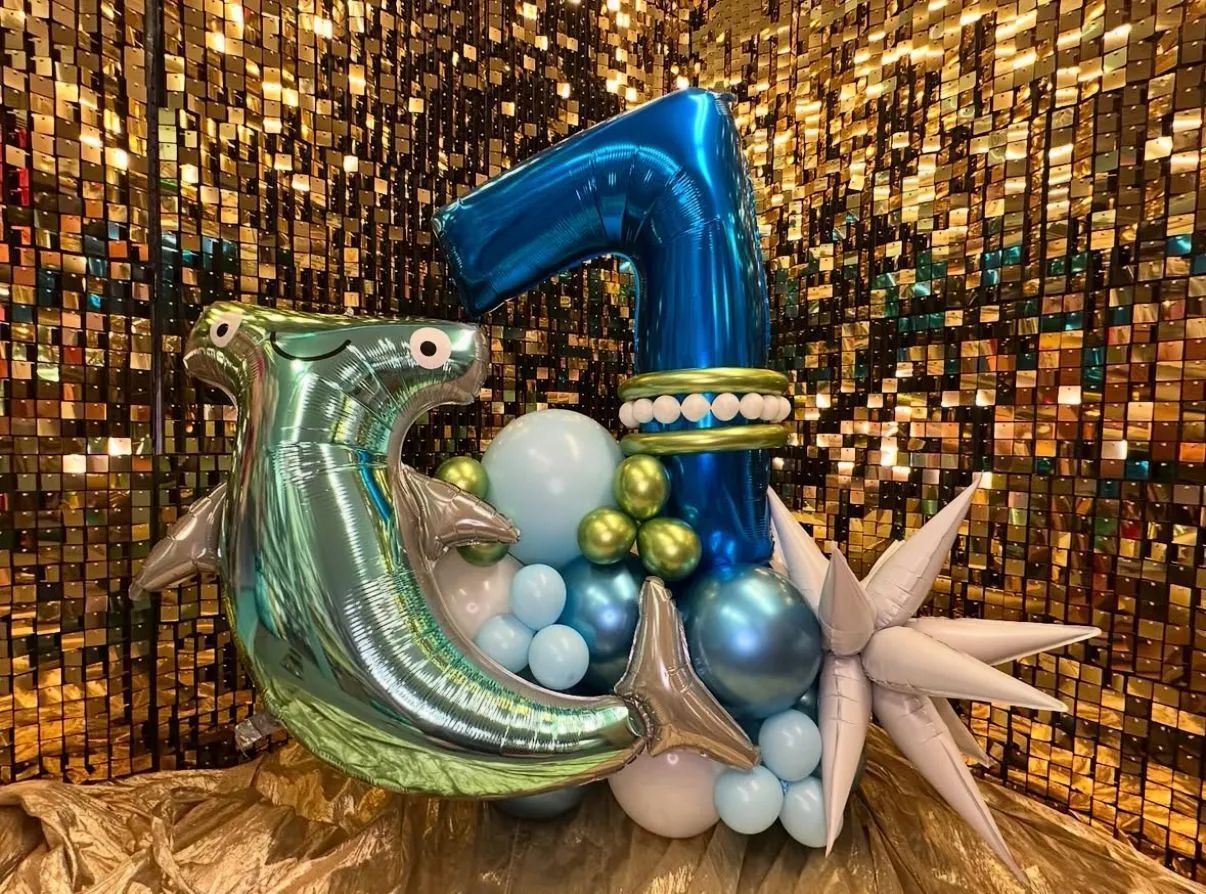 Balloon sculpture of the number 7 and crescent moon in blue, silver, and gold against a gold mosaic backdrop