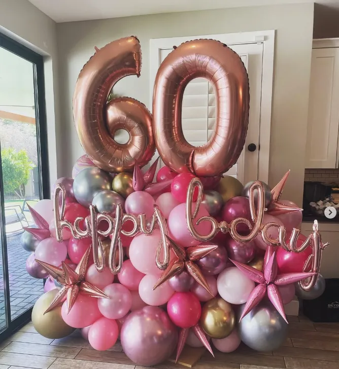 Pink and gold 60th birthday balloon display with “60” and “Happy Birthday” in a room