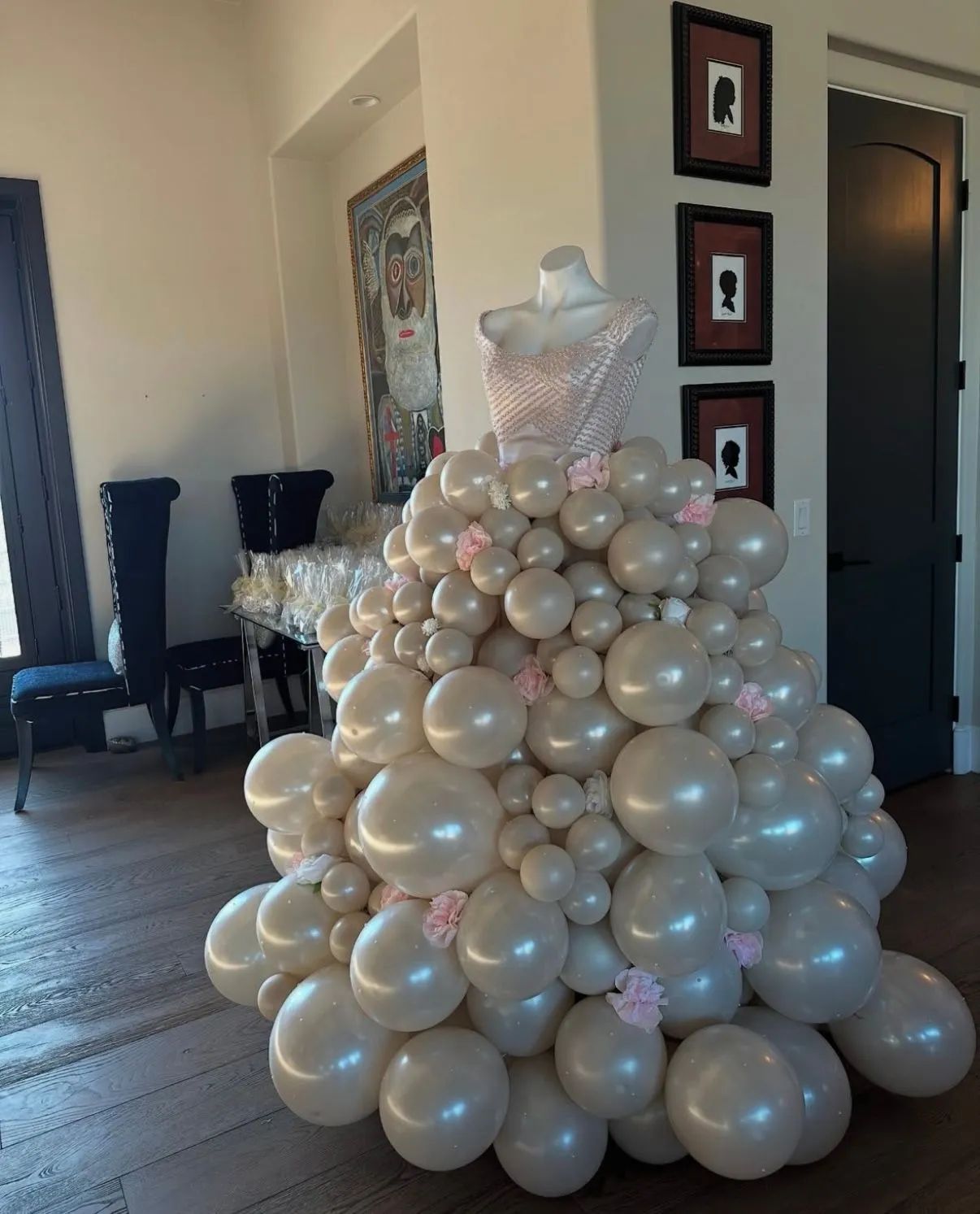 White balloon tower centerpiece in a room with dark chairs and framed wall art