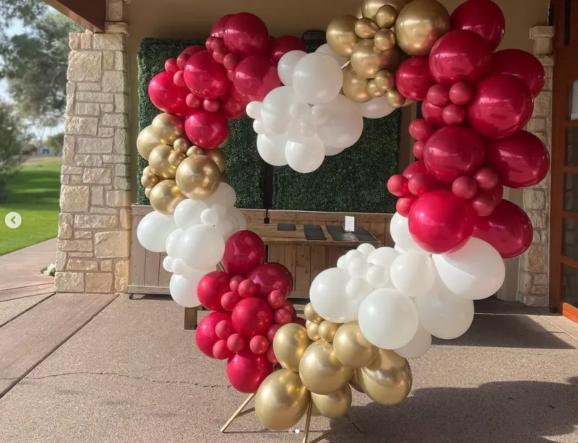Heart-shaped balloon wreath in red, white, and gold hanging on a storefront entrance