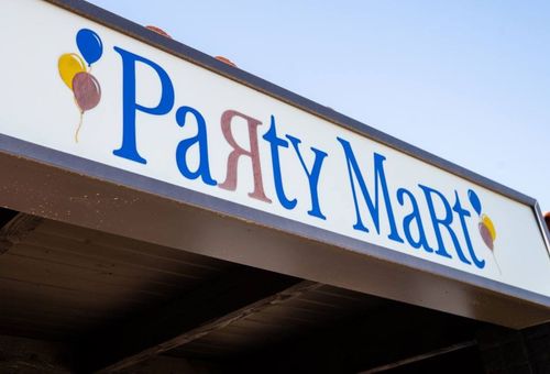 Party Mart storefront sign with blue lettering and balloon icons