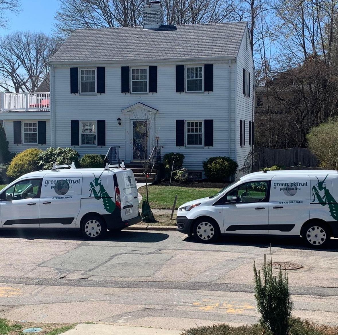 Two white vans are parked in front of a white house