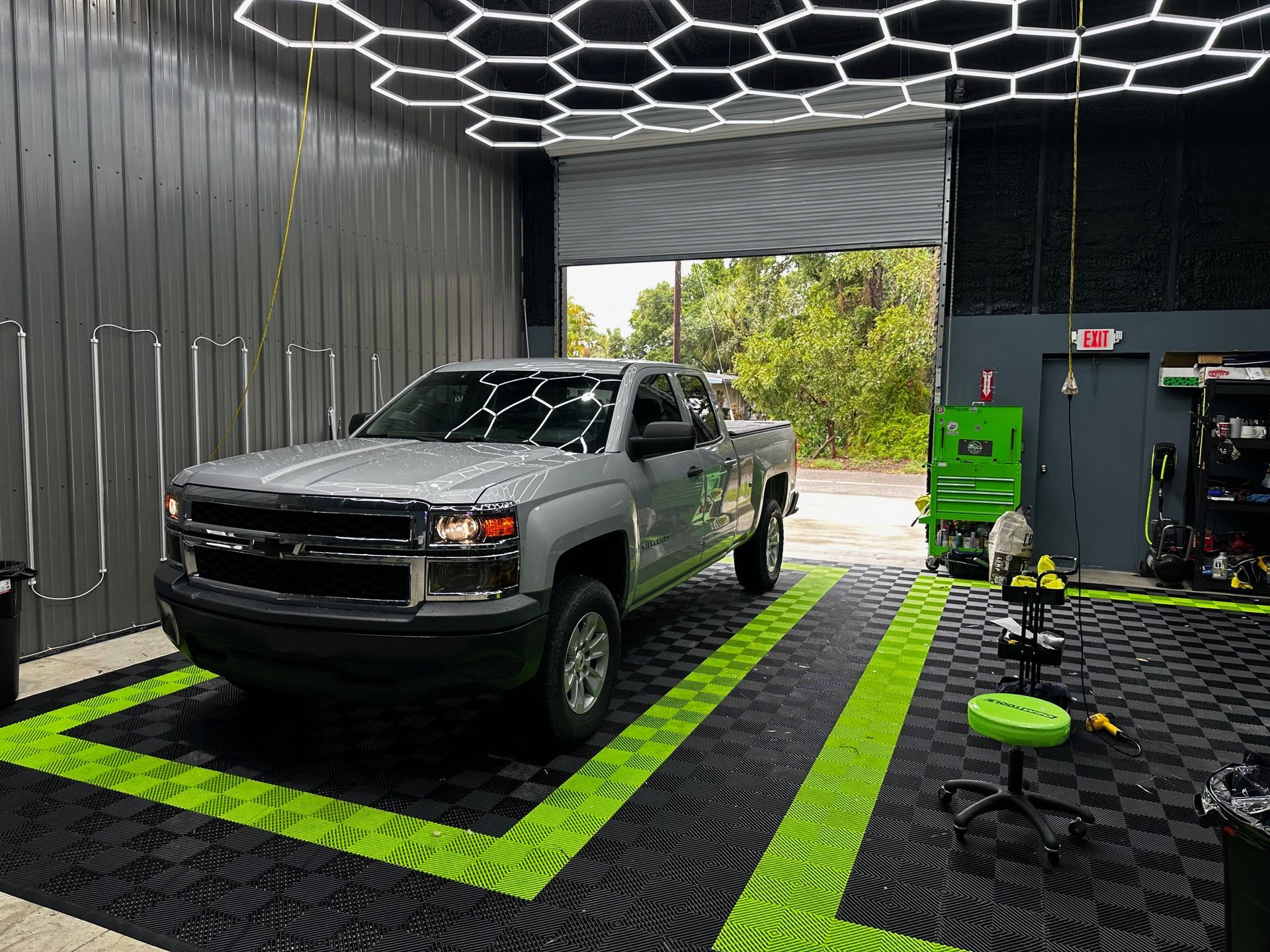A gray truck is parked in a garage with green stripes on the floor.