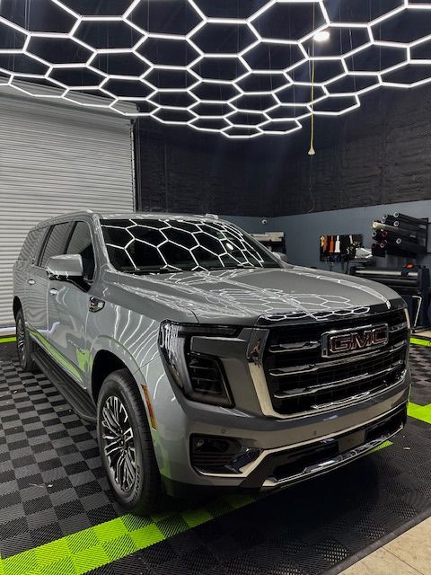 A gray gmc yukon is parked in a garage.