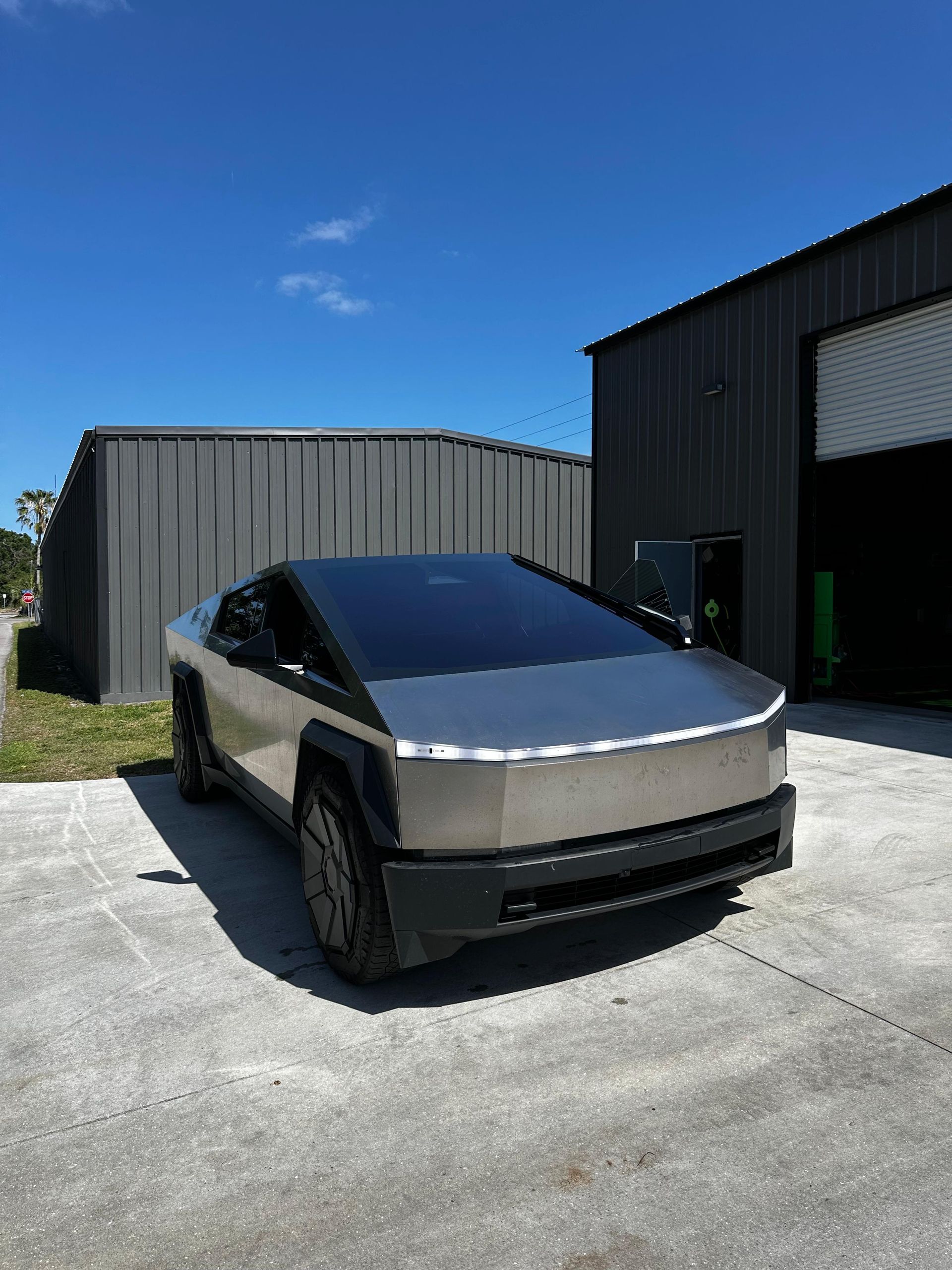 A silver tesla cybertruck is parked in front of a building.