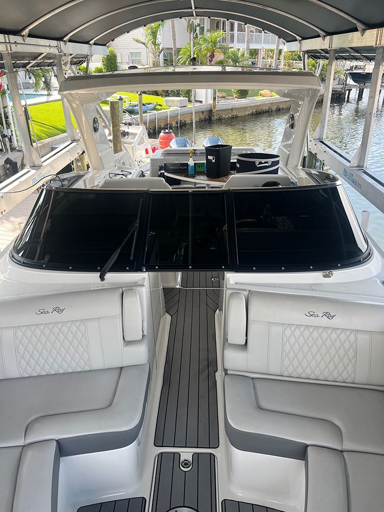 The inside of a boat with white seats and a black windshield.