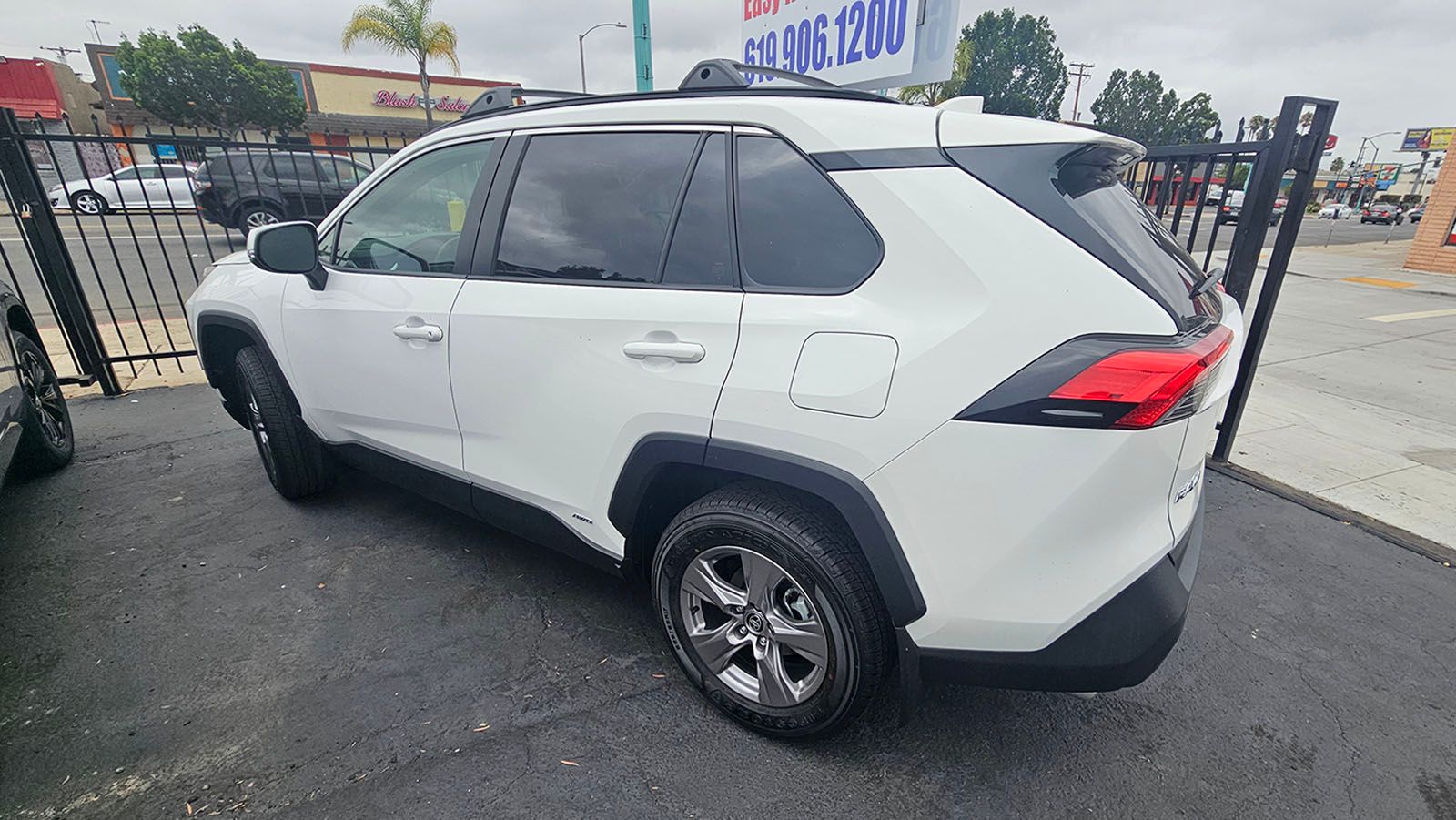 White SUV parked on pavement next to a metal fence