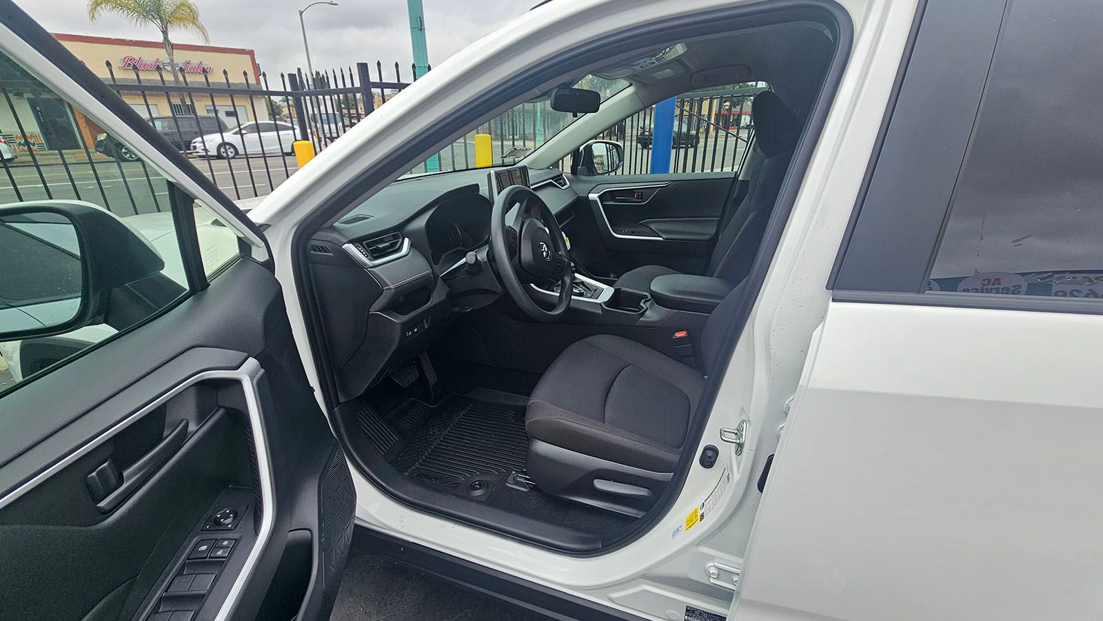 White SUV with driver's side door open, revealing black interior