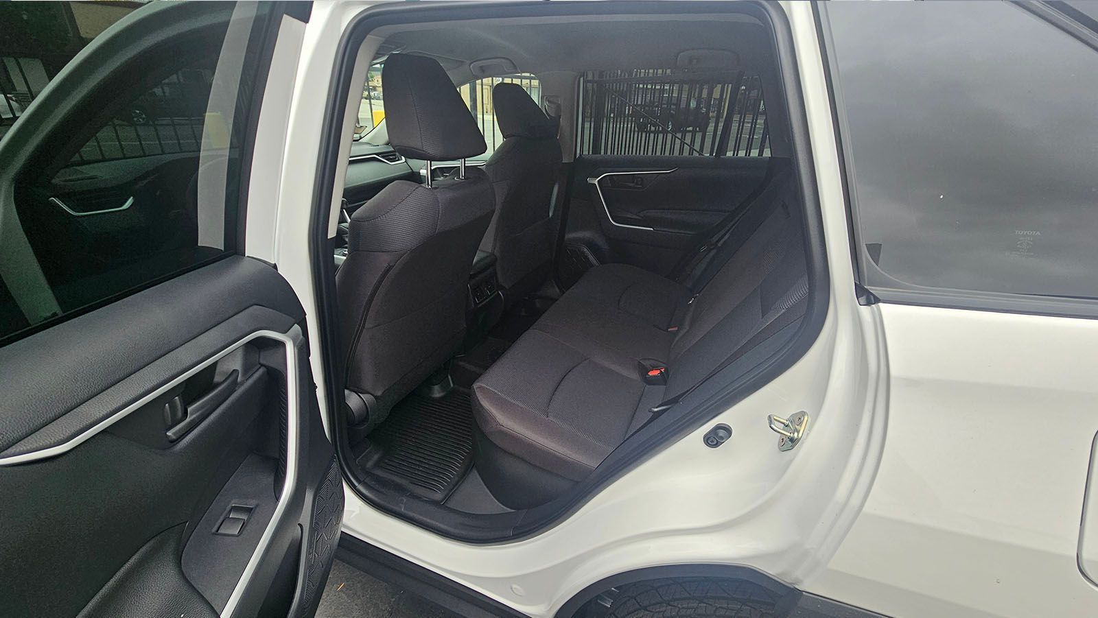 White car interior with open back door, showing rear seats and window sunshades