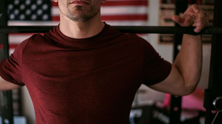 A man is squatting on a barbell in a gym.