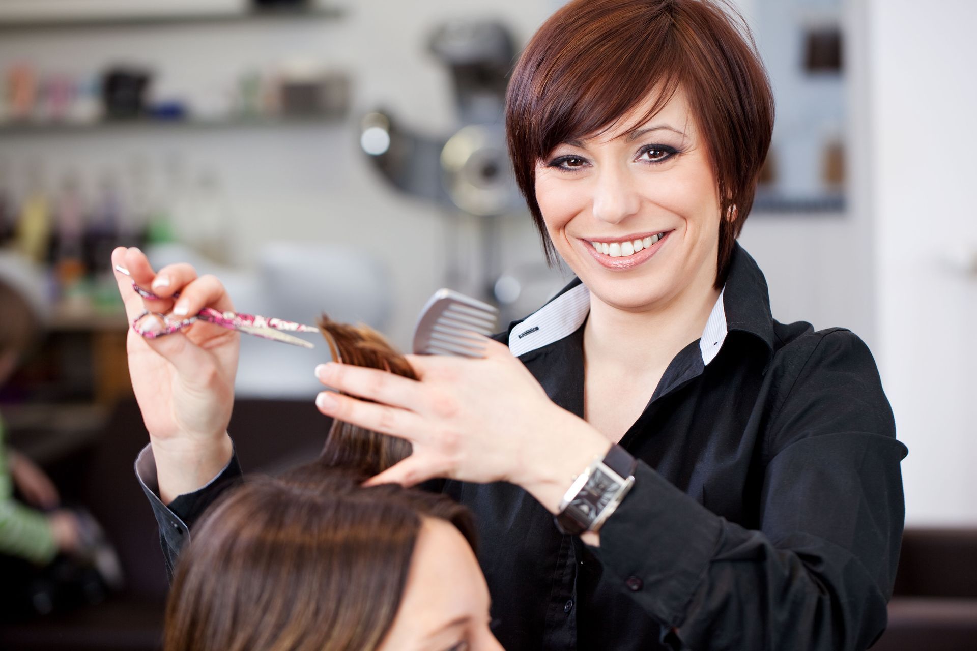 A woman is getting her hair cut by a hairdresser in a salon.